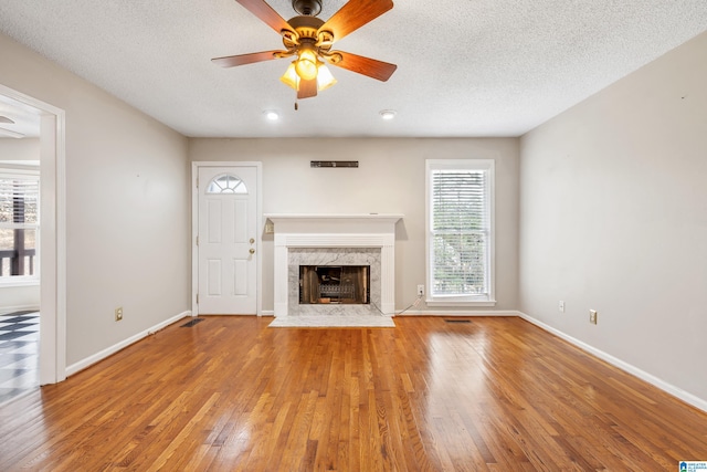 unfurnished living room with hardwood / wood-style flooring, ceiling fan, a textured ceiling, and a high end fireplace