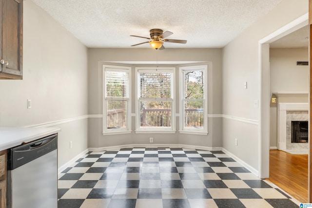 unfurnished dining area with a textured ceiling, a fireplace, and ceiling fan