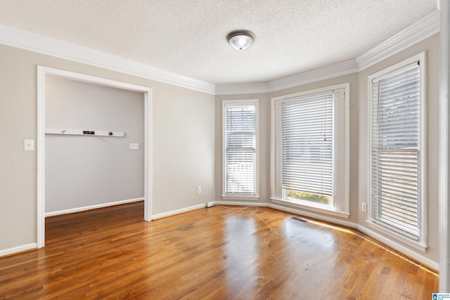 spare room with hardwood / wood-style floors, crown molding, and a textured ceiling