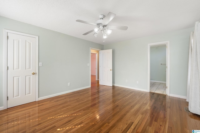 unfurnished bedroom featuring ceiling fan, hardwood / wood-style flooring, a textured ceiling, and ensuite bathroom