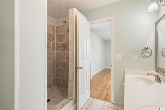 bathroom with vanity, a textured ceiling, and a tile shower