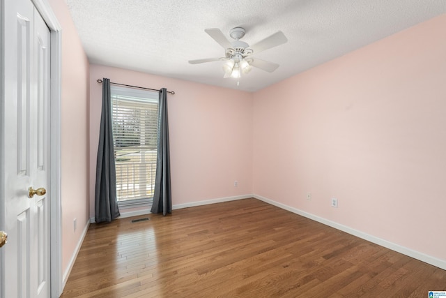 empty room featuring hardwood / wood-style flooring, ceiling fan, and a textured ceiling