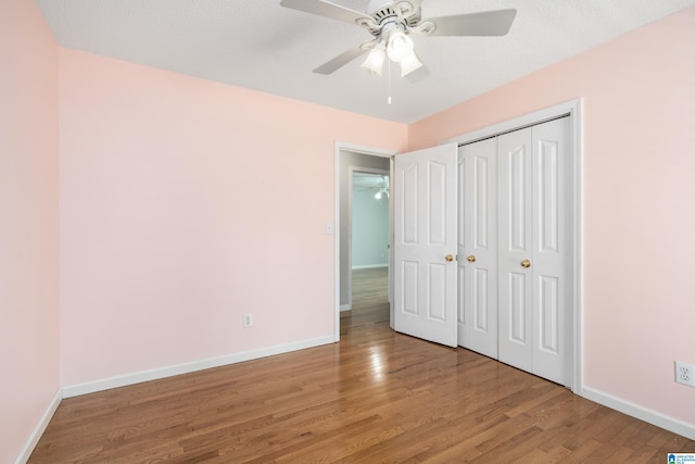 unfurnished bedroom with wood-type flooring, ceiling fan, and a closet