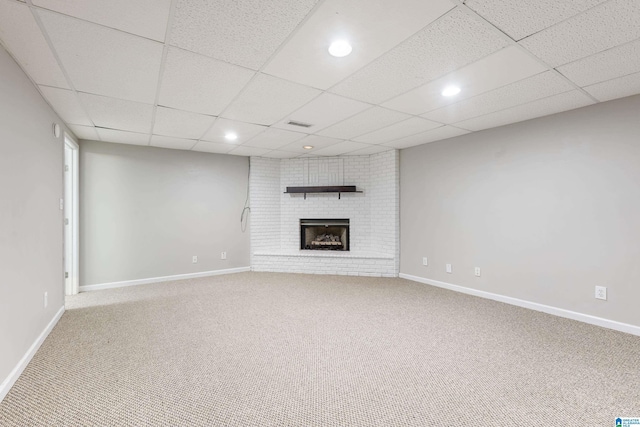 unfurnished living room featuring a brick fireplace, a paneled ceiling, and carpet flooring