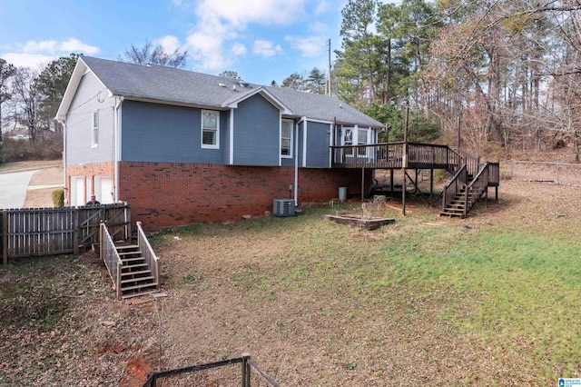 rear view of house featuring a wooden deck, central AC unit, and a lawn