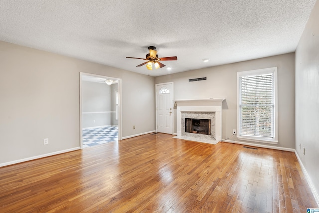 unfurnished living room with hardwood / wood-style flooring, a fireplace, a textured ceiling, and ceiling fan