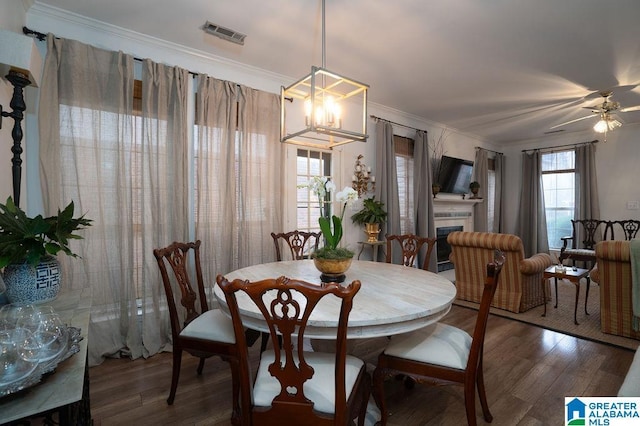 dining space with dark hardwood / wood-style flooring, crown molding, a tile fireplace, and ceiling fan