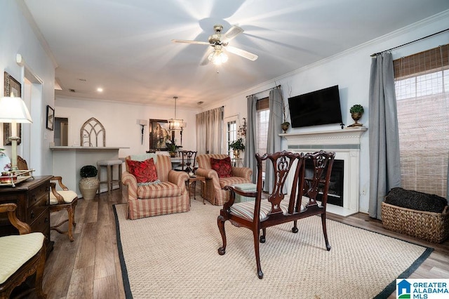 living room with hardwood / wood-style floors, ceiling fan with notable chandelier, and ornamental molding