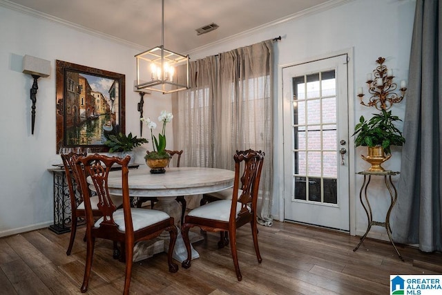 dining room with crown molding, dark wood-type flooring, and an inviting chandelier