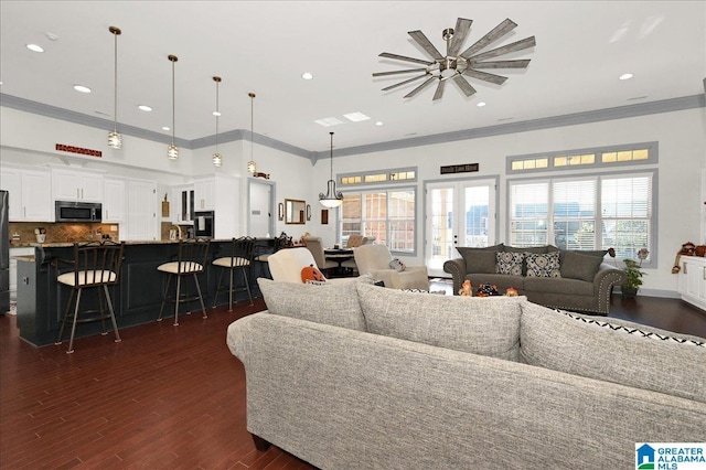 living room with french doors, a towering ceiling, crown molding, and dark wood-type flooring