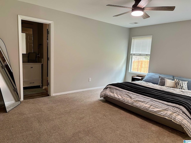 carpeted bedroom with a ceiling fan, visible vents, ensuite bath, and baseboards