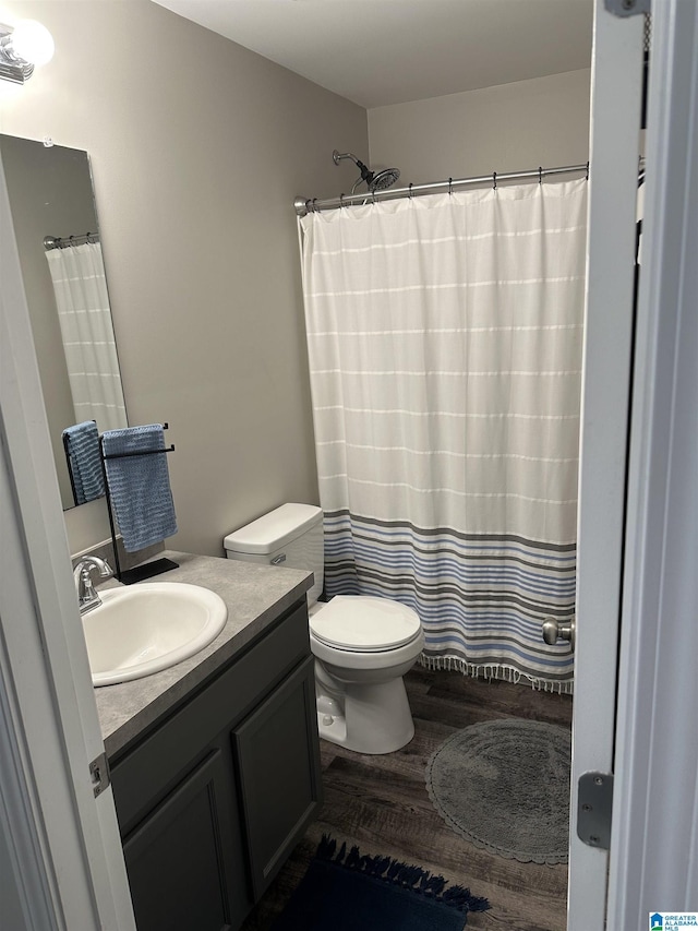 full bath featuring a shower with curtain, vanity, toilet, and wood finished floors