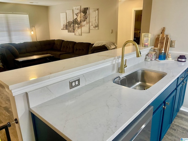 kitchen featuring open floor plan, a sink, dishwasher, and blue cabinets