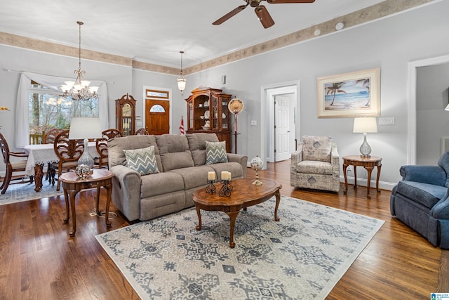 living room featuring ceiling fan with notable chandelier, dark wood-type flooring, and ornamental molding