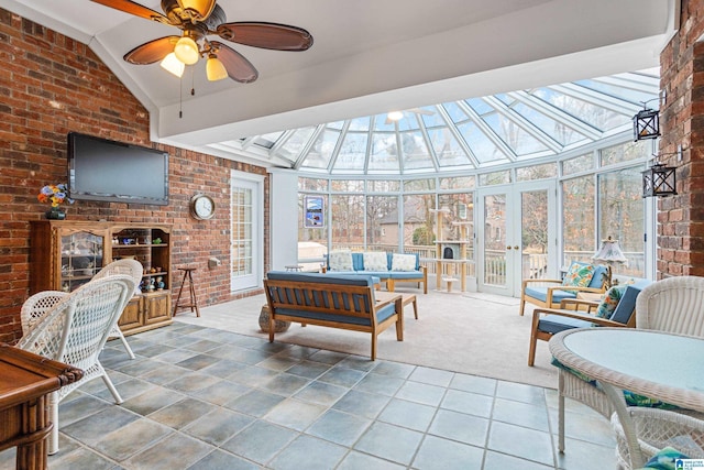 sunroom / solarium with a fireplace, lofted ceiling with skylight, and ceiling fan