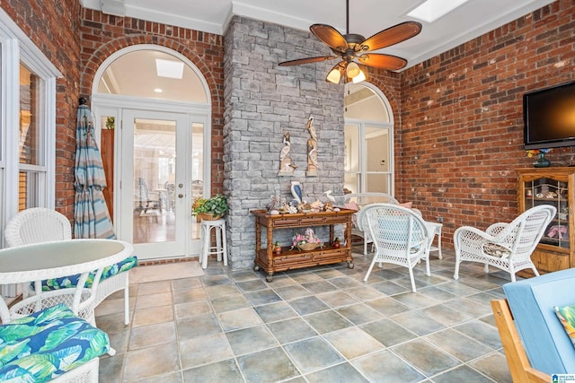 interior space featuring ceiling fan and brick wall