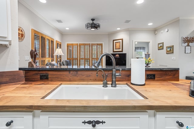 kitchen with white cabinetry, sink, and crown molding