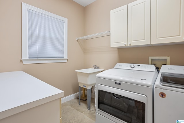 washroom with light tile patterned flooring, cabinets, and washer and dryer