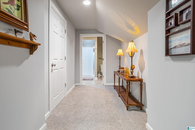 hall with lofted ceiling and light carpet