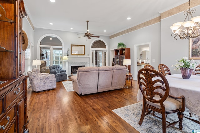 living room with ornamental molding, dark hardwood / wood-style flooring, and ceiling fan with notable chandelier