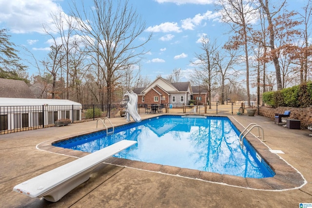 view of swimming pool featuring a patio, a water slide, and a diving board