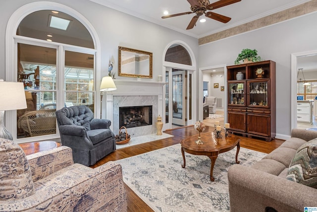 living room with ceiling fan, ornamental molding, a high end fireplace, and hardwood / wood-style floors