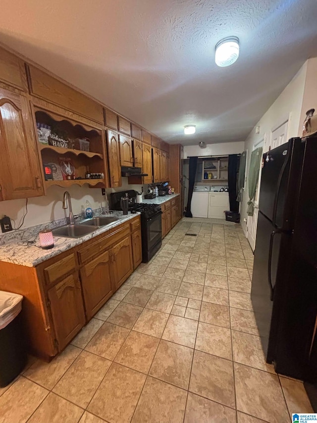 kitchen featuring black appliances, sink, light tile patterned floors, a textured ceiling, and washer and clothes dryer