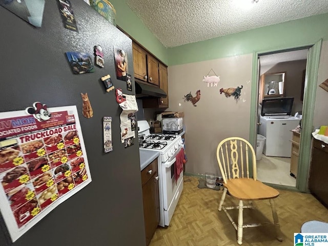 kitchen featuring stainless steel refrigerator, light parquet floors, white range with gas stovetop, a textured ceiling, and washer / clothes dryer