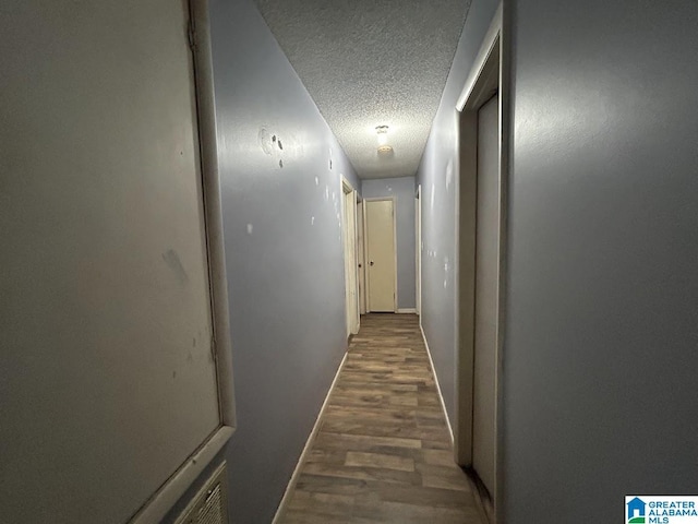 corridor with dark hardwood / wood-style flooring and a textured ceiling