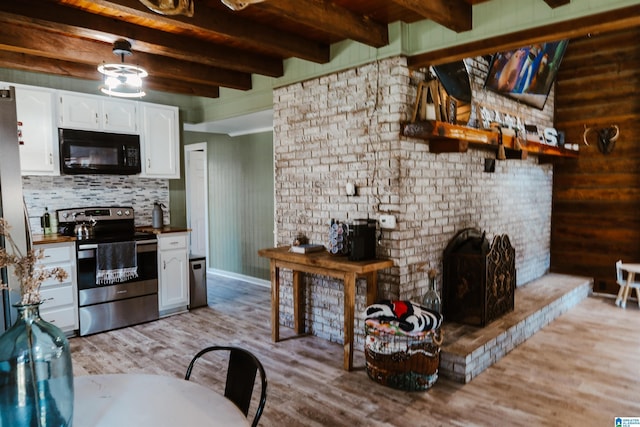 kitchen with beam ceiling, stainless steel electric range oven, light wood-type flooring, a fireplace, and white cabinets