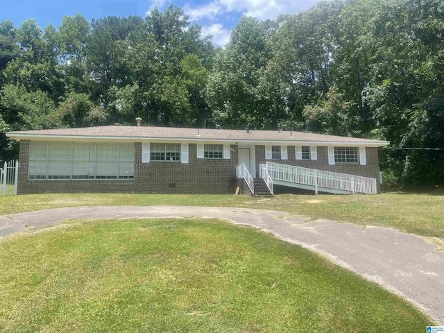 view of front of home with a front yard, crawl space, brick siding, and driveway