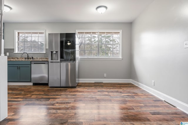 kitchen with appliances with stainless steel finishes, dark wood-type flooring, dark countertops, and baseboards