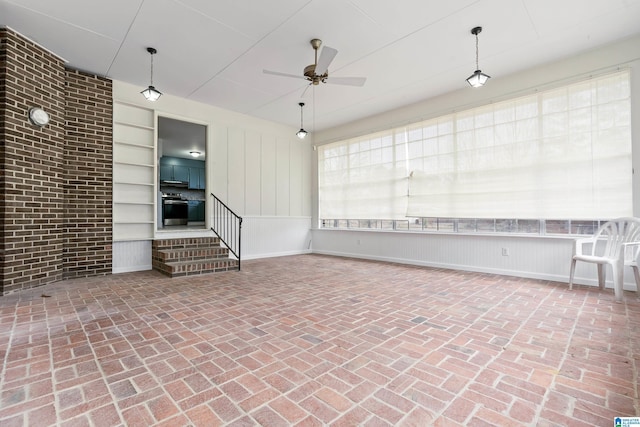 interior space with brick floor, built in features, and a ceiling fan