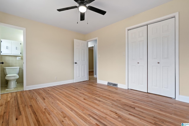 unfurnished bedroom with ensuite bathroom, a closet, light wood-type flooring, and visible vents