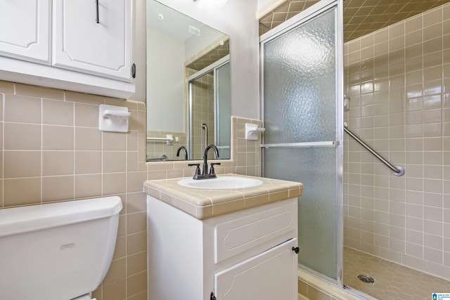 full bath featuring toilet, a stall shower, vanity, and tile walls