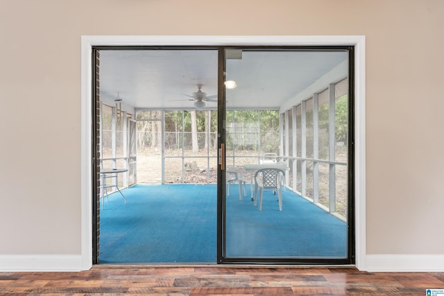 doorway featuring a sunroom, floor to ceiling windows, baseboards, and wood finished floors