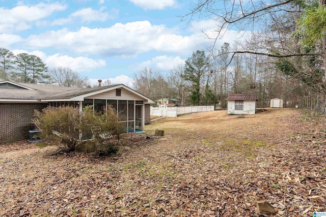 view of yard with an outbuilding, a sunroom, fence, and a storage shed