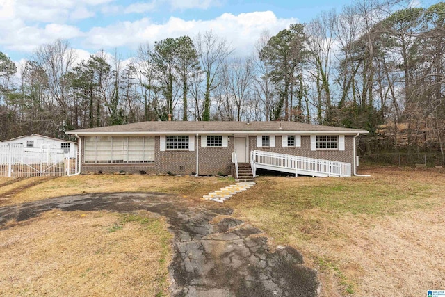 view of front of property with a front yard, brick siding, and fence