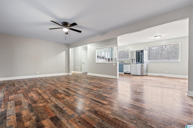 unfurnished living room featuring baseboards, visible vents, a ceiling fan, and dark wood-type flooring