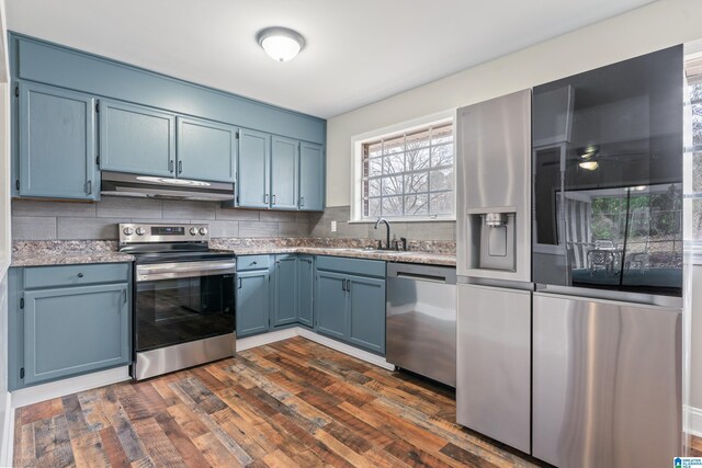 kitchen with under cabinet range hood, appliances with stainless steel finishes, and blue cabinetry