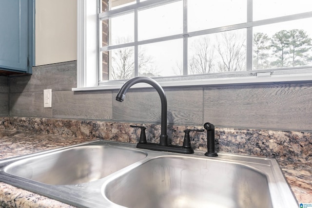 interior details featuring blue cabinetry, decorative backsplash, and a sink