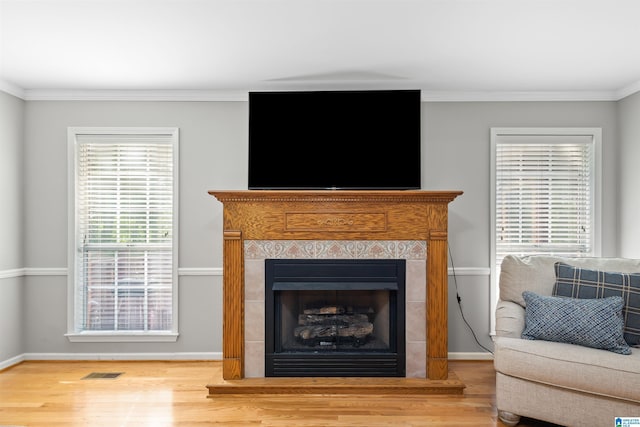 living room with a tiled fireplace, hardwood / wood-style floors, and crown molding