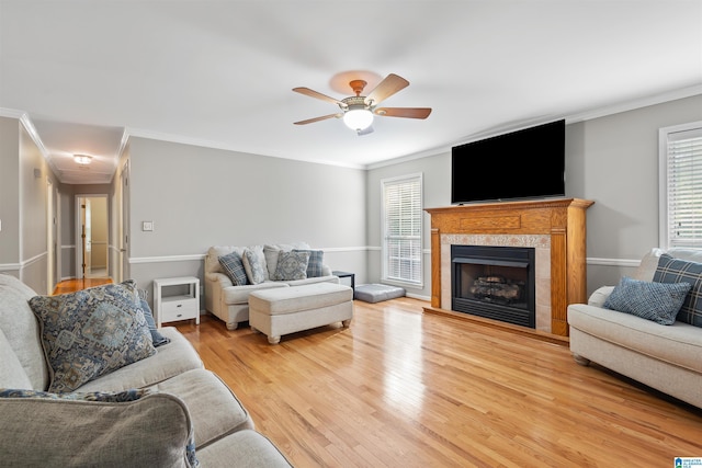 living room featuring ornamental molding, ceiling fan, a fireplace, and light hardwood / wood-style flooring