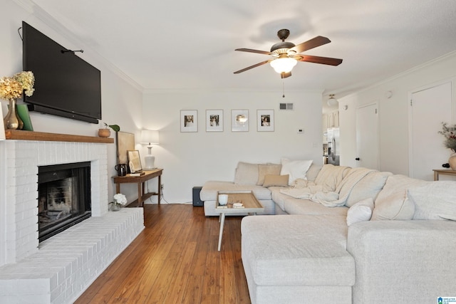 living room featuring ornamental molding, a brick fireplace, and hardwood / wood-style floors