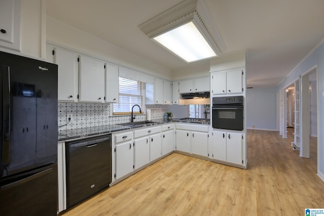 kitchen with tasteful backsplash, white cabinetry, sink, black appliances, and light wood-type flooring