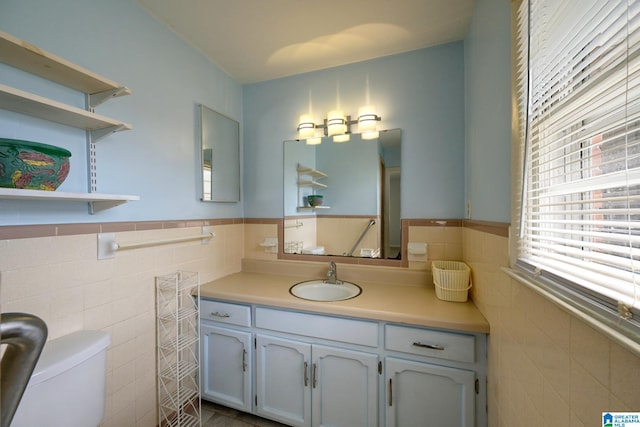 bathroom with tile walls, vanity, and toilet