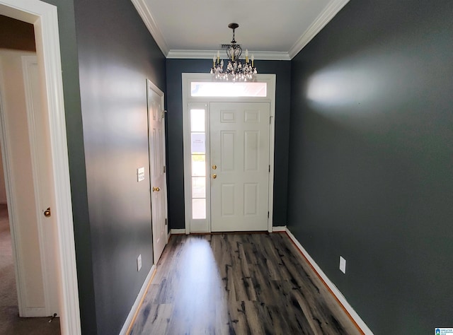 entrance foyer with dark wood-type flooring, ornamental molding, and a chandelier