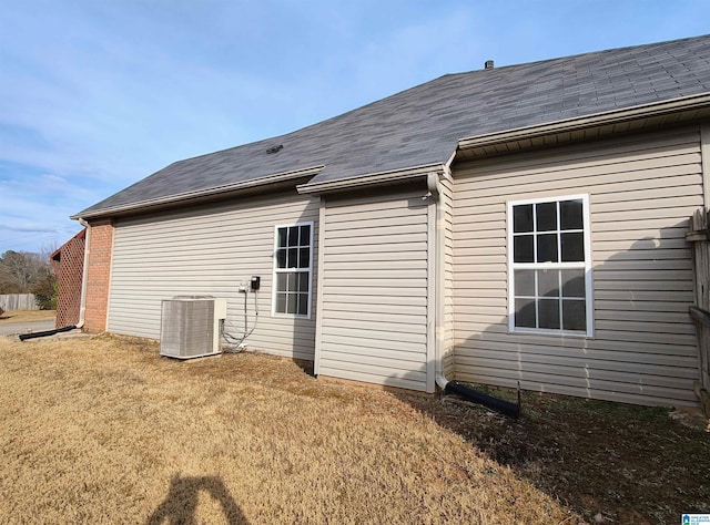 rear view of house featuring cooling unit and a lawn