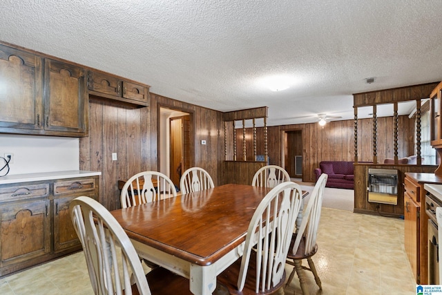 dining area featuring a textured ceiling, heating unit, and wood walls