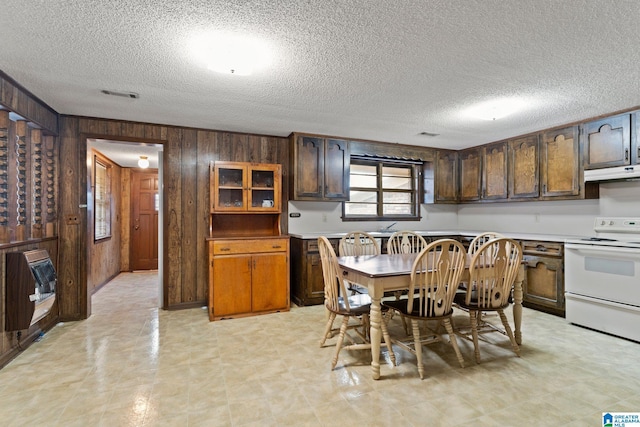 kitchen with dark brown cabinetry, white electric range oven, heating unit, wood walls, and a textured ceiling